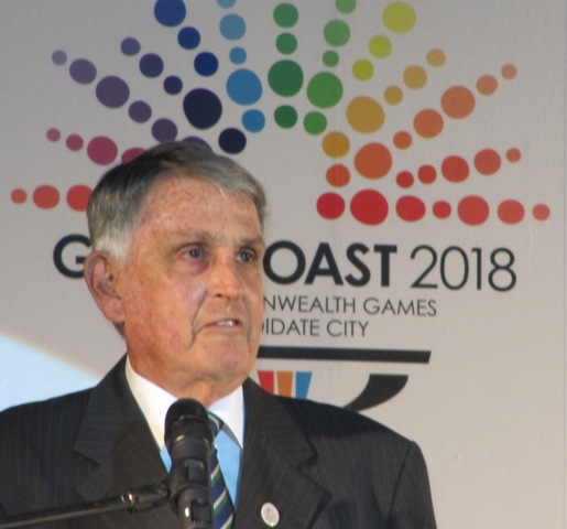 Ron Clarke_in_front_of_Gold_Coast_2018_logo