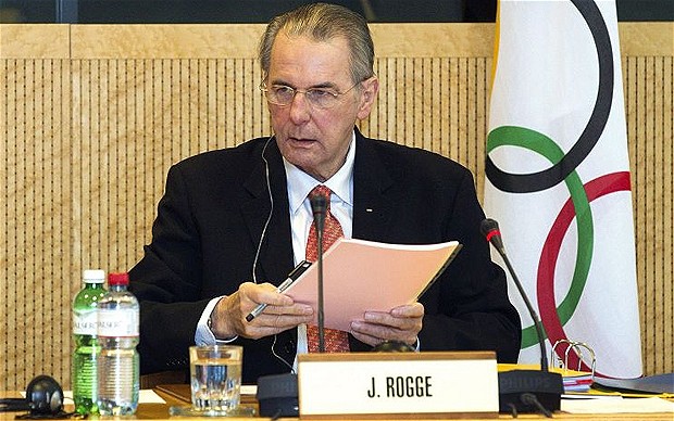 Jacques Rogge_behind_name_badge_and_in_front_of_IOC_flag