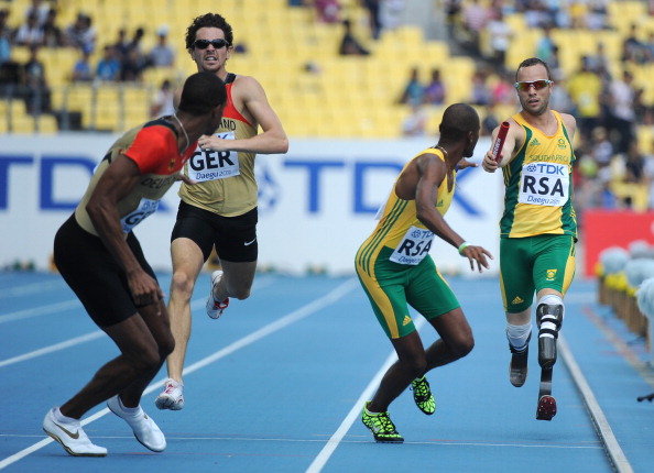 South Africas_first_leg_runner_Oscar_Pistorius_R_hands_the_baton_to_South_Africas_Ofentse_Mogawane_2R_as_Germanys_Jonas_Plass_2L_hands_off_to_Germanys_Kamghe_Gaba_18-07-12