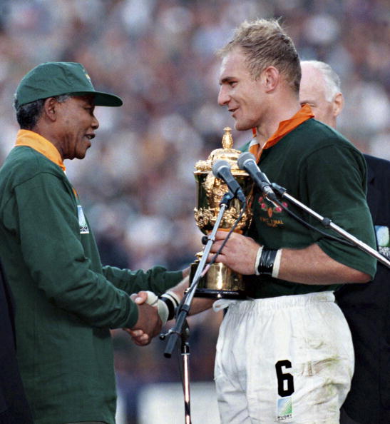 South African president Nelson Mandela dressed in a No 6 Springbok jersey congratulates the Springbok captain Francois Pienaar after South Africa beat the All Blacks by 15-12 to win the 1995 Rugby World Cup