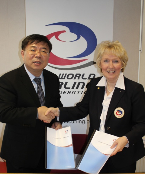 Chinese Curling Association President Ni Huizhong and WCF President Kate Caithness with the contracts for the WMCC 2014