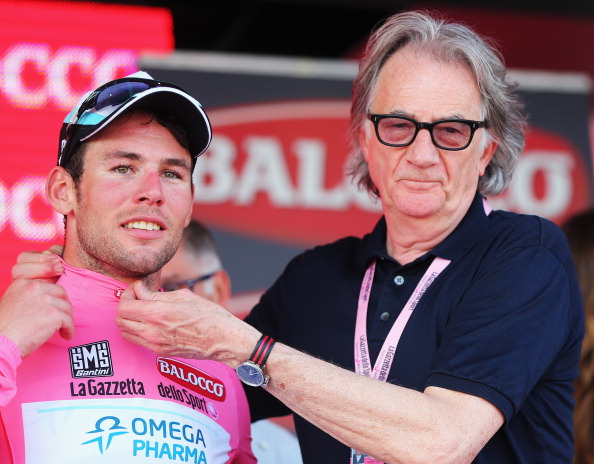 Mark Cavendish of Great Britain and Omega Pharma - Quick-Step pulls on the Maglia Rosa with help from fashion designer Paul Smith following his victory in stage one