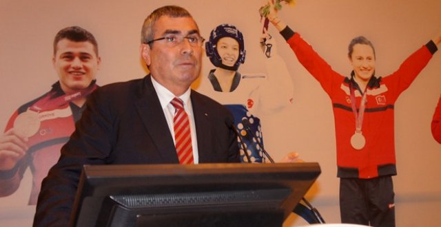 Uğur Erdener in front of Turkish athletes sign