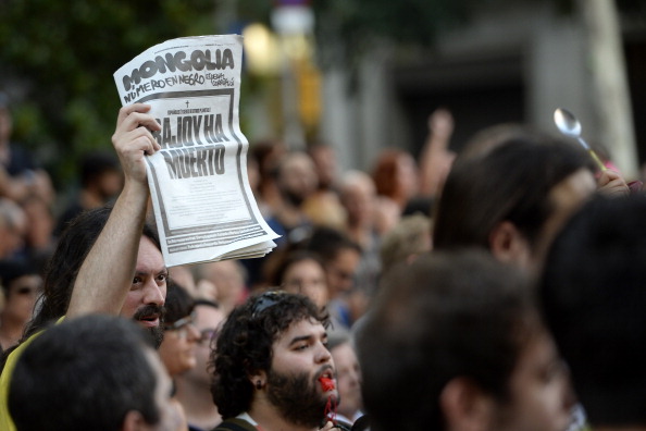 protesters holds a copy of the newspaper Mongolia reading Rajoy is dead during a demonstration against corruption outside the People Partys headquarters in Barcelona