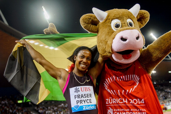 Jamaica's Shelly-Ann Fraser-Pryce celebrates flanked by the 2014 European Championships mascot after she won the women's 200 metres of the Diamond League meeting