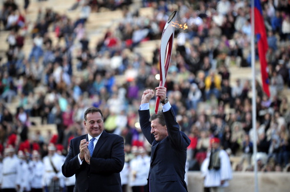 Russian Deputy Prime Minister Dmitry Kozak holds aloft the Olympic Torch after it has been passed to Sochi 2014