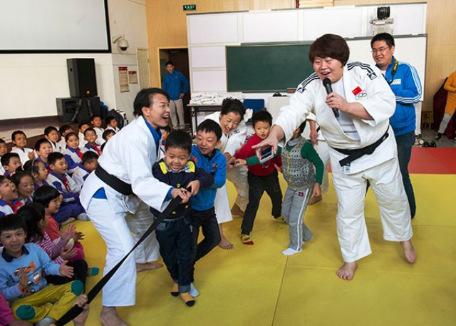 Olympic champion Tong Wen (right) gets children moving on a visit back to her old primary school © IJF Media