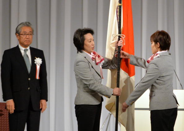 Head of Japan's Winter Olympic delegation Seiko Hashimoto (centre) hands the national flag to the Japan team flag bearer during the ceremony ©AFP/Getty Images