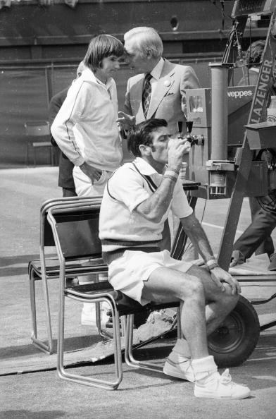 Ken Rosewall takes a break and a drink during his three-sets defeat in the 1974 Wimbledon final to 18-year-old Jimmy Connors, pictured behind him ©Getty Images