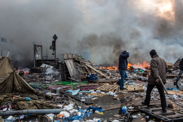 Anti-government protesters walk amid debris and flames near the perimeter of Independence Square ©AFP/Getty Images
