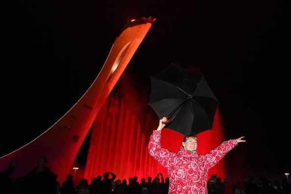A spectator dances with an umbrella in front of a water and light show after the Flame is lit ©Getty Images