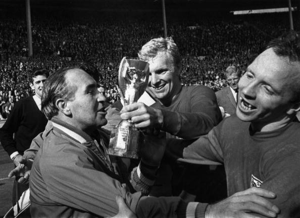 Nobby Stiles (right) tries to get his England manager Alf Ramsey to take part in a lap of honour with the Jules Rimet trophy - being passed to him by captain Bobby Moore - after England's World Cup victory in 1966. Ramsey, naturally, refused. ©Hulton Archive/Getty Images