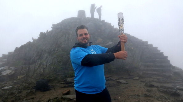 Aled Davies held the Glasgow 2014 Queen's Baton aloft at the summit of Snowdon in Wales ©Getty Images
