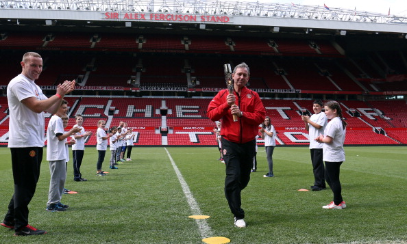 Former England international Bryan Robson carries the Queen's Baton around the pitch at Old Trafford, home to his old club Manchester United ©Glasgow2014/Getty Images