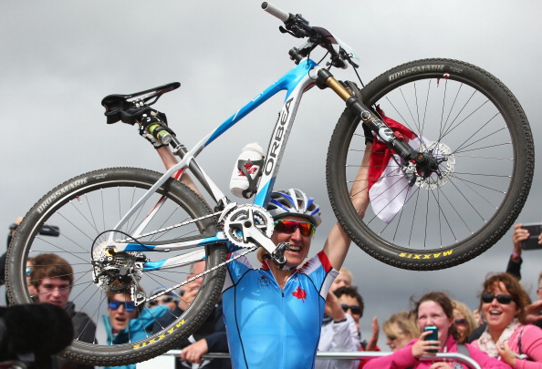 Catharine Pendrel of Canada holds her bike aloft in celebration at winning the women's cross-country mountain biking ©Getty Images