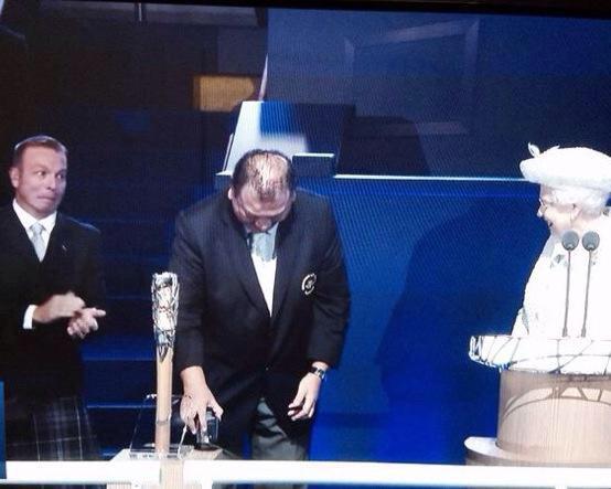 The Queen smiles and Sir Chris Hoy looks, well, bemused as Prince Imran struggles to open the Baton ©Twitter