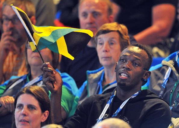 Usain Bolt, who has denied describing the Glasgow 2014 Games as "a bit sh**", waves the flag for Jamaica's women netballers during yesterday's match against New Zealand ©AFP/Getty Images