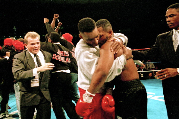 Mike Tyson is shepherded away after losing his heavyweight titles to 42-1 outsider Buster Douglas in 1990 after a 10th round ko in their fight in Tokyo ©Getty Images