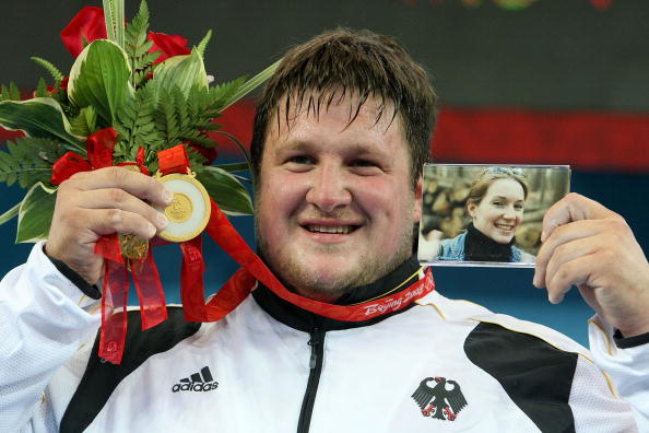 Matthias Steiner posing on the Beijing 2008 podium with a photo of his late wife ©Getty Images