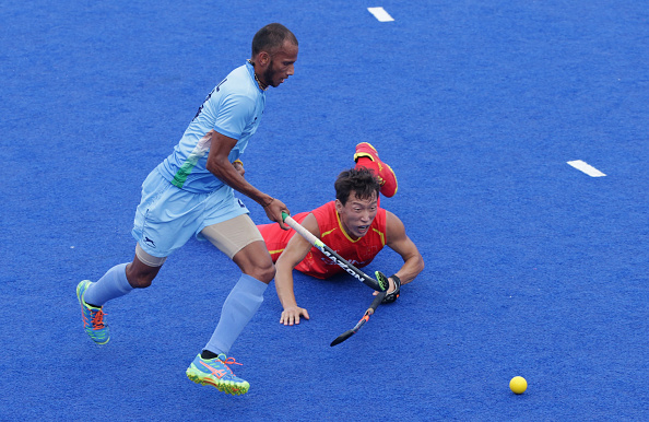 A fall for Ao Weibao of China as Indian Sowmarpet Vitalacharya ran with the ball in their men's hockey Pool B contest ©AFP/Getty Images